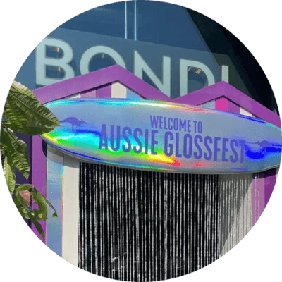 Aussie Gloss Fest entrance with a colourful sign and glossy festival-style booth at Bondi Green