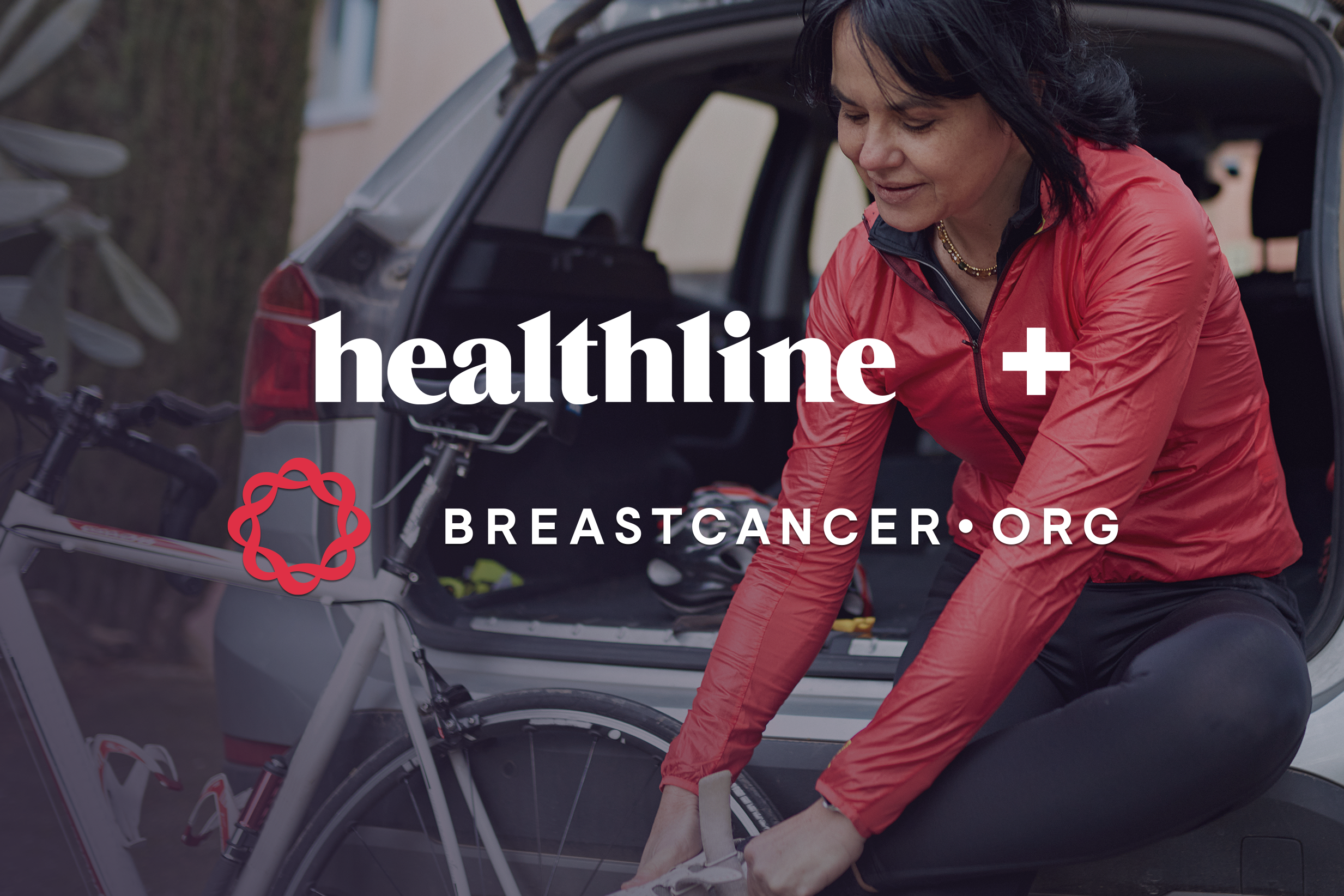 A woman in a red shirt is preparing for a bike ride. Healthline and Breastcancer.org logos overlay the image.