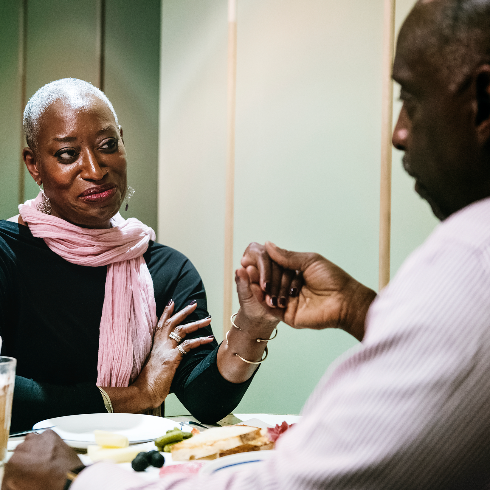 Older couple holding hands at dining table