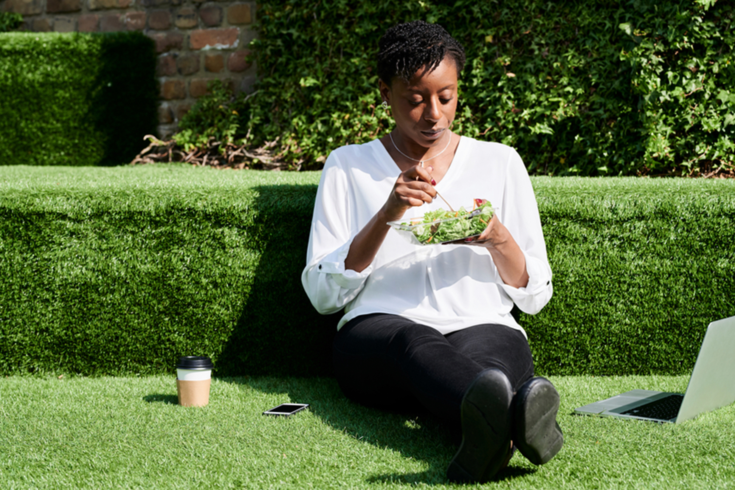 Woman sitting outside eating salad