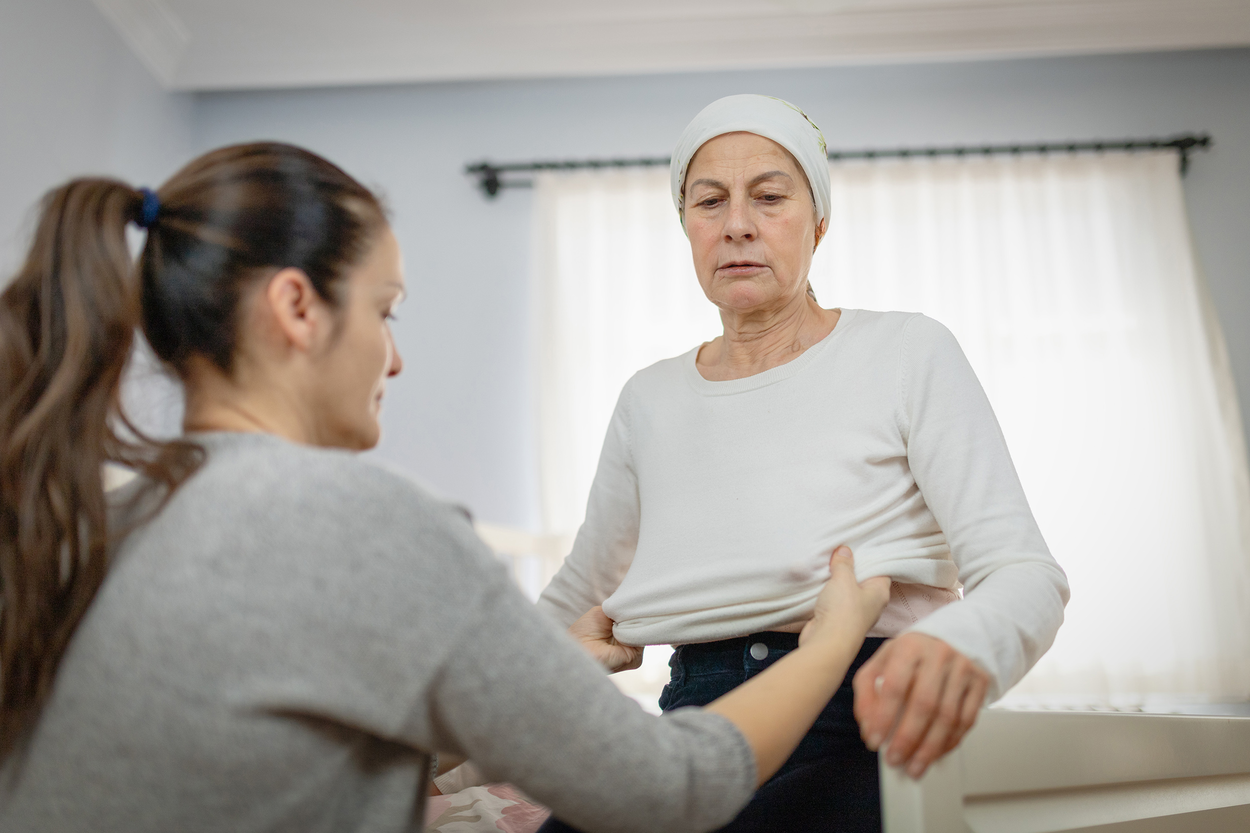 caregiver helping woman put on clothes