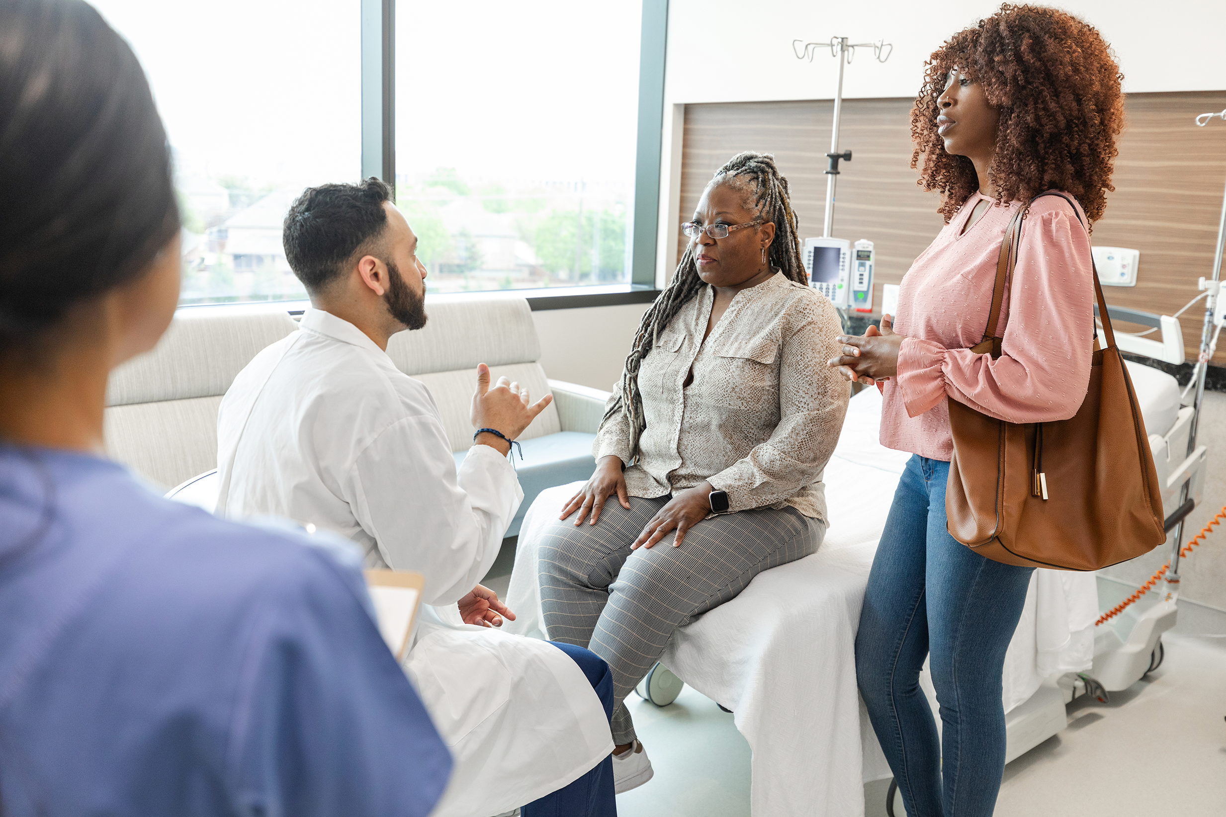 Two Black women taking to a doctor in an exam room.