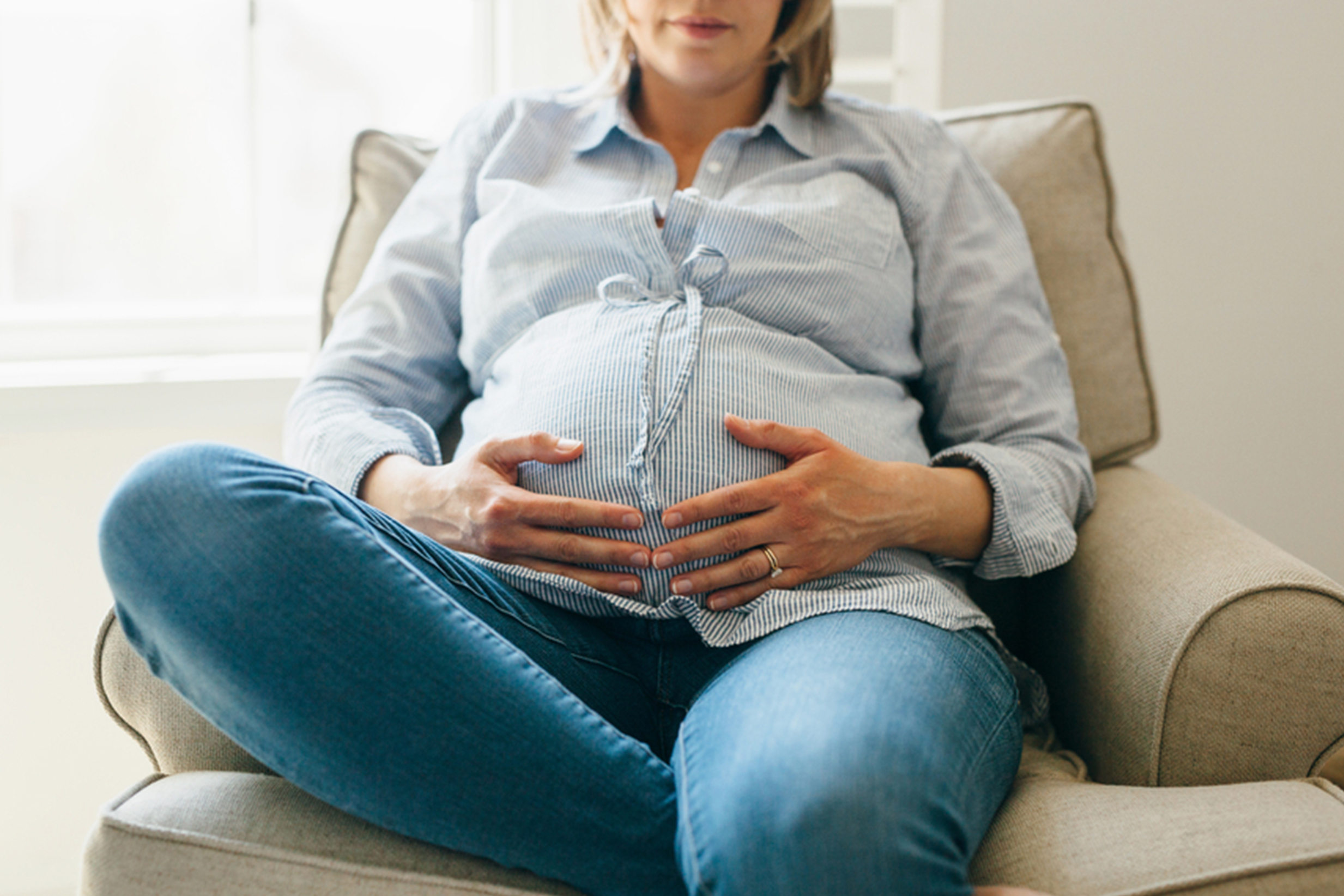 Pregnant woman in jeans sitting on chair