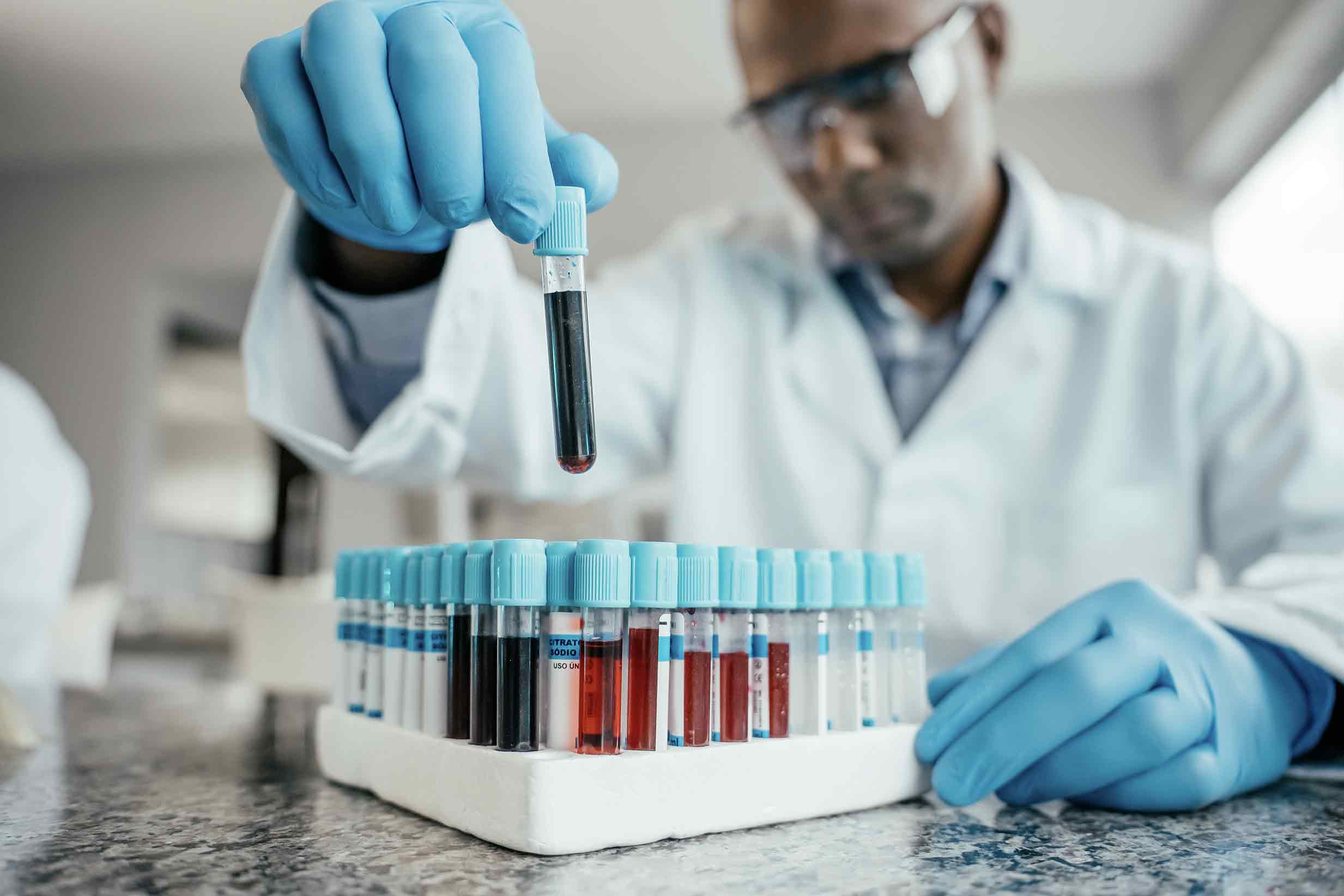 Researcher lifts test tube from set of other test tubes.