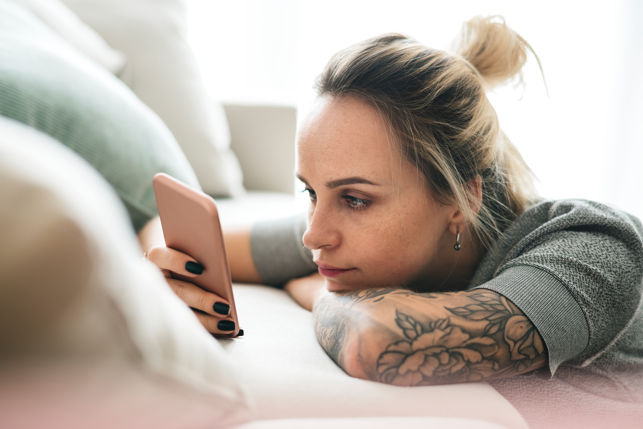 Young woman with arm tattoos looking at phone